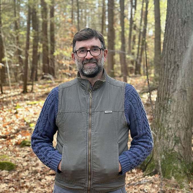 Photo of Matt Kelly smiling and standing in the woods. Photo links to Matt’s staff bio.